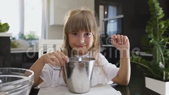 小有趣的女孩在碗里煮面粉肖像拍摄小女孩用勺子搅拌面粉视频的预览图