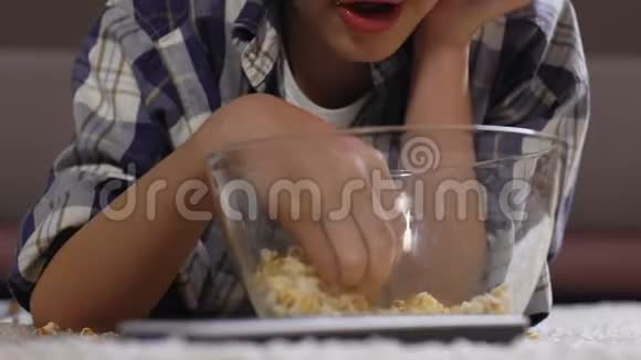 男孩在家看3d电影时吃爆米花不健康的生活方式懒惰视频的预览图