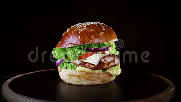 快餐有烤排骨青菜番茄和洋葱的汉堡在黑色背景的木板上慢慢旋转视频的预览图