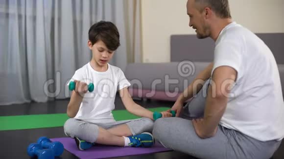 微笑的爸爸在家庭锻炼时表扬儿子教他做健身运动视频的预览图