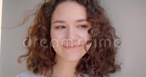年轻可爱长头发卷曲的白种人女模特幸福地笑着看着摄像机的特写镜头视频的预览图
