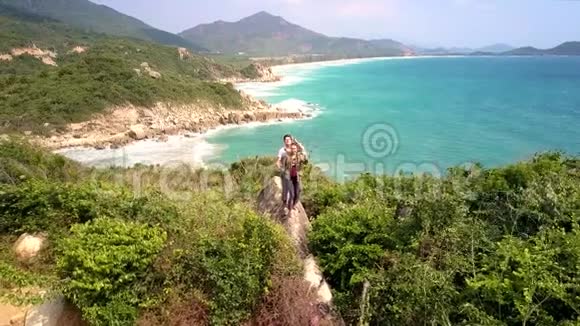 一对夫妇站在悬崖边上双手对抗海景视频的预览图