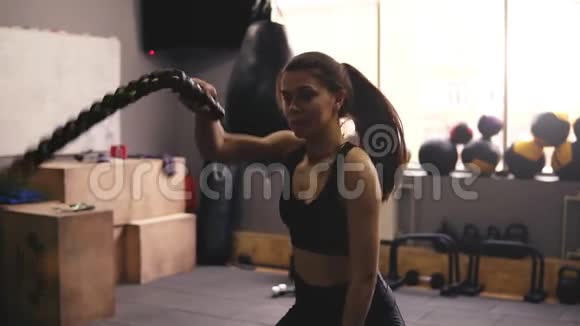 在健身房里一个20的健壮的黑发女孩在表演战斗绳索锻炼视频的预览图
