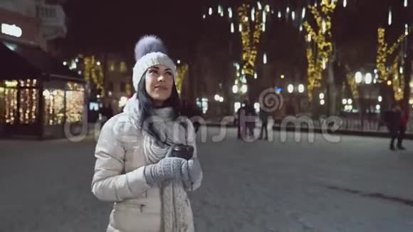 女孩穿着温暖的衣服在夜晚的城市照明视频的预览图