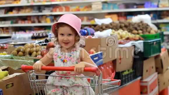 商店折扣出售超市里的小女孩坐在购物车里视频的预览图