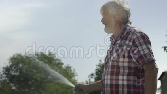 老人用水管给草地浇水视频的预览图