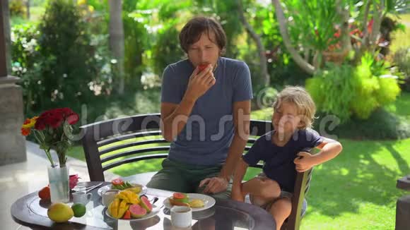 一位年轻的父亲和他的小儿子吃了一顿牛油果早餐吃了很多水果这是一个缓慢的镜头视频的预览图
