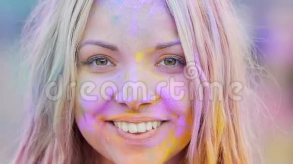 绘有彩色粉末的嬉戏女孩微笑着摆姿势拍照特写视频的预览图