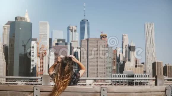 在长椅上欣赏令人惊叹的曼哈顿天际线景色留着长发的快乐女性旅行者的后景视频的预览图