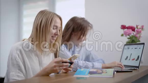 两个年轻女孩的朋友在网上商店买鞋子一个女人用信用卡付款视频的预览图