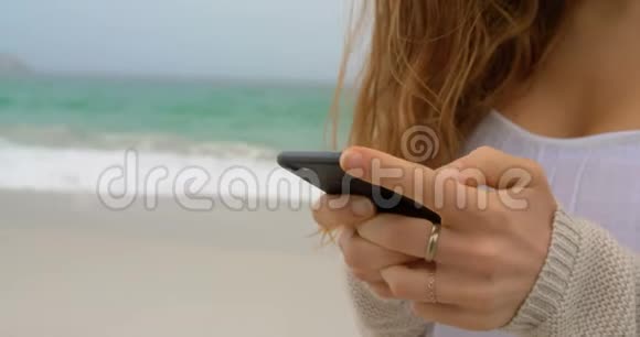 在海滩上使用手机的中间部分视频的预览图