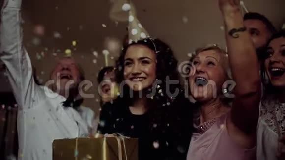 一个多代家庭的肖像在室内生日聚会上有一个蛋糕纸屑掉落视频的预览图