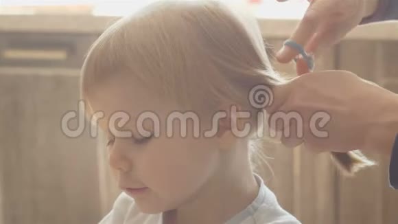 一个有魅力的女人为她的小女儿做她的发型妈妈给小女儿做尾巴发型视频的预览图