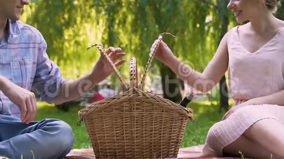 年轻夫妇从野餐篮子里拿出酒杯和酒瓶结婚纪念日视频的预览图