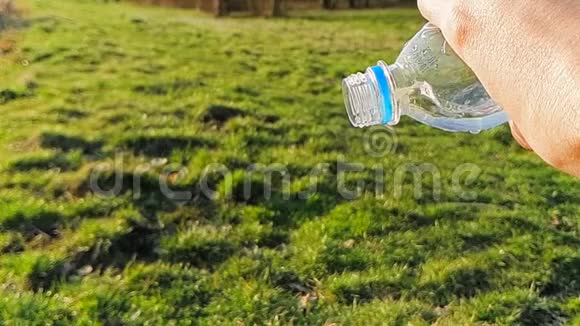 特写的水从塑料瓶里流出背景是绿草1000FPS慢速运动视频的预览图