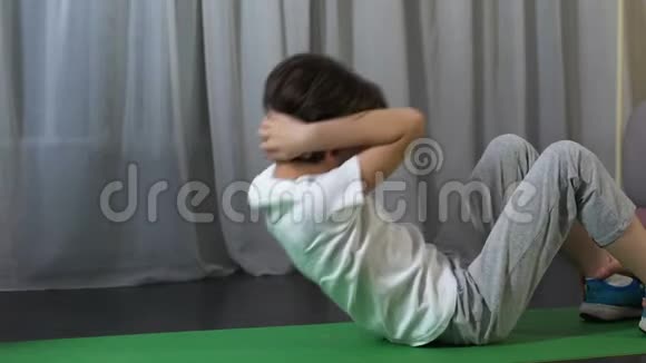 小男孩做腹部皱褶父亲抱着脚踝做体力活动视频的预览图
