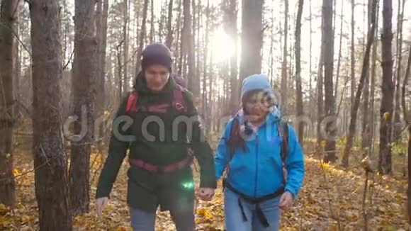 一对徒步旅行者在秋天的森林里背包徒步旅行积极休息的概念视频的预览图