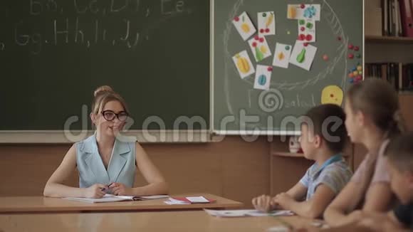 女老师在小朋友面前教室里的漂亮老师坐在桌子前问孩子们教育视频的预览图