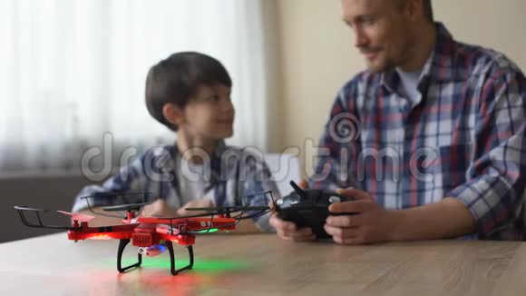 有趣的爸爸在家里操作四架飞机快乐的儿子在看新的无人机游戏视频的预览图