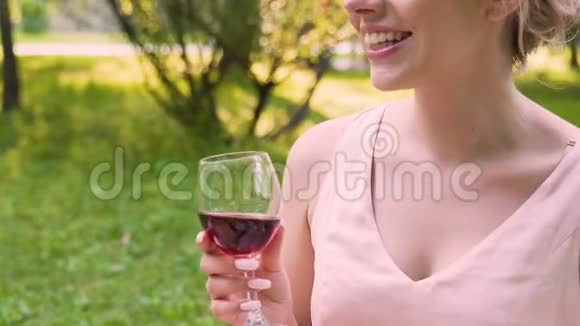 快乐的女人和朋友交谈手里拿着酒杯坐在公园里活动视频的预览图