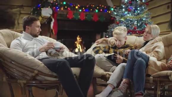成年男子和一个小男孩在圣诞夜与一本书和一个女人交谈视频的预览图