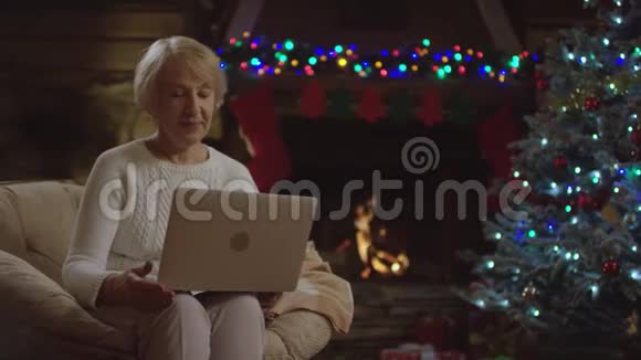 圣诞夜老太太在网上用笔记本电脑播放视频的预览图