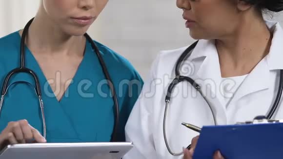 年轻护士和成人医生讨论诊断在平板电脑中插入数据视频的预览图