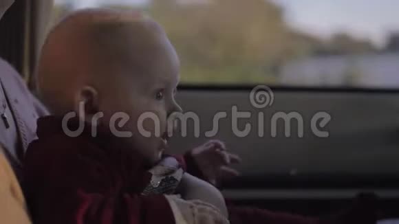 可爱的女婴坐在妈妈的车上好奇地看着路视频的预览图