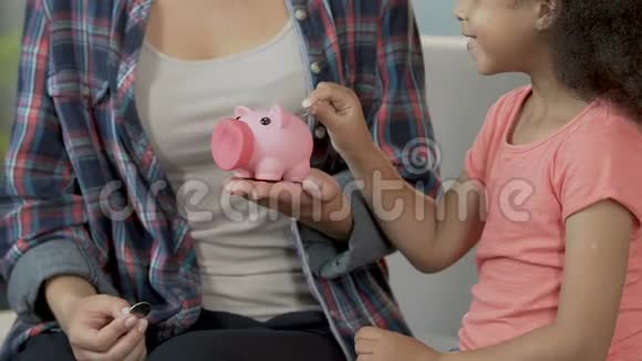 母亲和女儿把硬币放在储蓄罐里经济责任储蓄视频的预览图