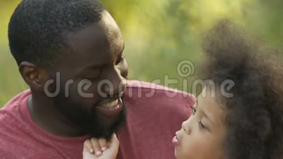 可爱的小女孩在外面和她微笑的父亲玩耍笑着拥抱着视频的预览图