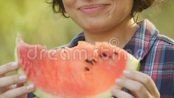 年轻女子在夏季野餐时吃多汁西瓜微笑着吃维生素视频的预览图