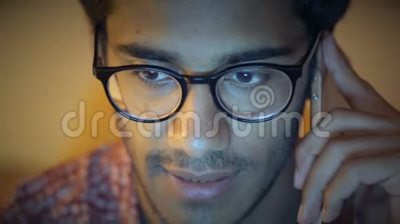 特写镜头戴眼镜的印度男人在电脑后面打电话讨论商业问题视频的预览图