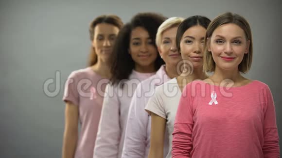 穿着粉色衬衫和乳腺癌丝带的快乐女人站在一起视频的预览图