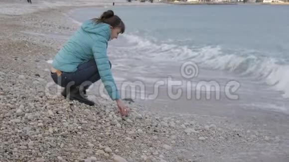 孤独寒冷海滩的女人白种人女人从迎面而来的海浪中跳出来在水面上玩石头视频的预览图