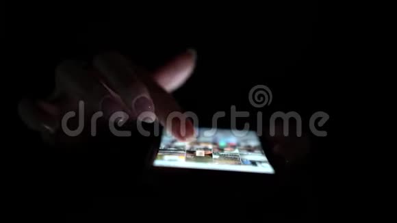 女人使用智能手机晚上的时间快关门黑色背景视频的预览图