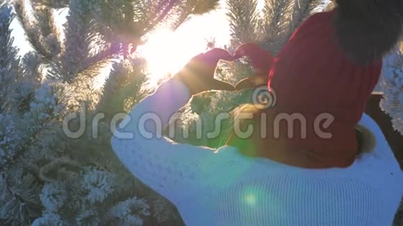 冬日夕阳下女性手举太阳耀斑做心形手势视频的预览图