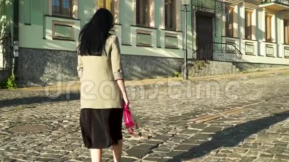 自信又时髦的黑发女郎慢动作地走在城市的石路上视频的预览图