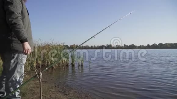 杆固定在河岸上的专用棒中渔夫站在附近看着水河流捕鱼慢慢视频的预览图