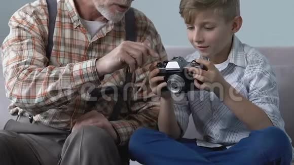 祖父展示男孩老式照片相机创造性的家庭爱好休闲视频的预览图