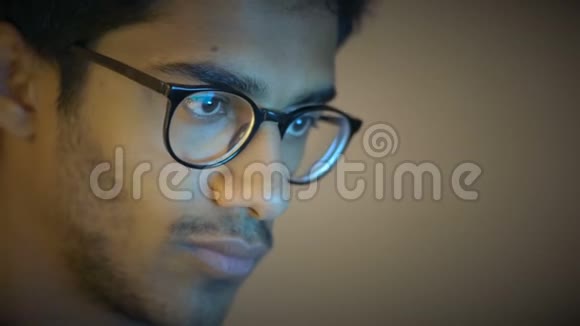 特写镜头戴眼镜的印度男孩看手提电脑屏幕做家务视频的预览图
