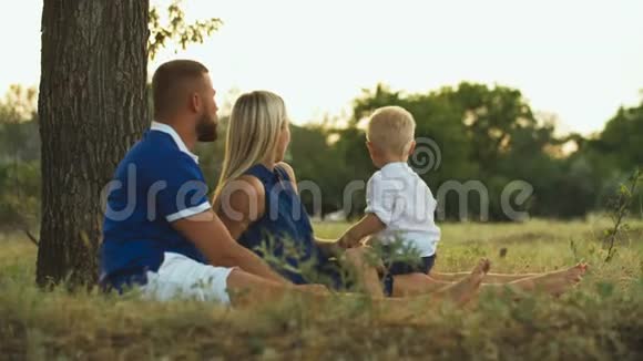 幸福的家庭坐在草地上看着奶牛视频的预览图
