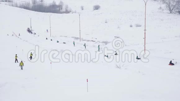 寒假人们从山上骑着充气雪管孩子们爬山背着雪橇冬季视频的预览图