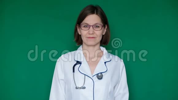 微笑自信的女医生穿着实验室外套看着绿色屏幕上的相机Chroma键关门视频的预览图
