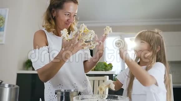 漂亮漂亮的妈妈和她的小女儿在一起做饭的时候试图用面团清洁他们的手视频的预览图