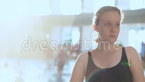 一个穿着黑色泳衣的年轻女孩站在一个公共室内水上公园的背景下视频的预览图