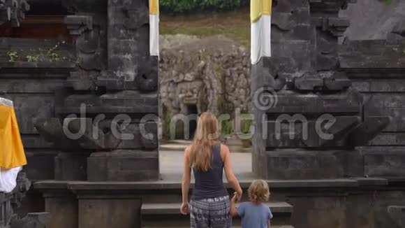 一名年轻女子和她的小儿子在巴厘岛乌布德村参观大象洞GoaGajah的慢镜头视频的预览图