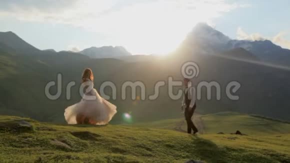 日落时分一个男人和一个女孩穿着一件华丽的衣服视频的预览图