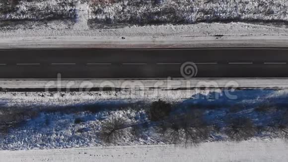 在阳光充足的阳角拍摄的冬季道路上方的空中飞景视频的预览图