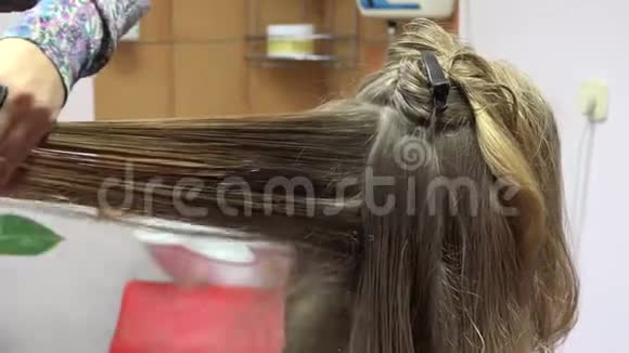 美容师在美容院做长发女人的发型4K视频的预览图