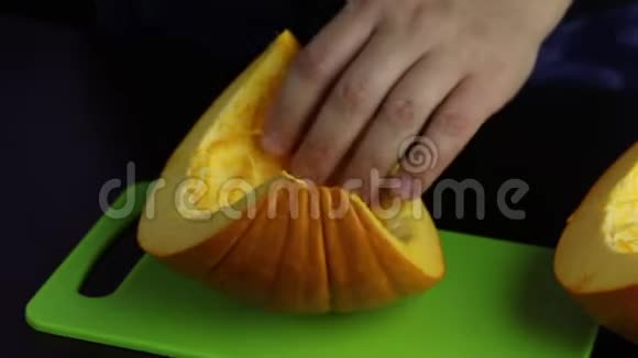 一个人用刀子在切割板上切南瓜南瓜是橙色的世界素食日视频的预览图